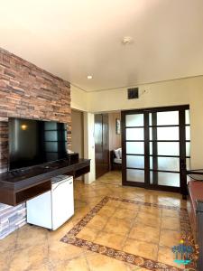 a living room with a tv and a brick wall at Palmas Del Mar Resort Bacolod in Bacolod