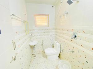 a white bathroom with a toilet and a sink at Hotel Safko Suites in Bangalore +34 photos