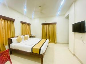 a bedroom with a bed and a flat screen tv at Hotel Safko Suites in Bangalore