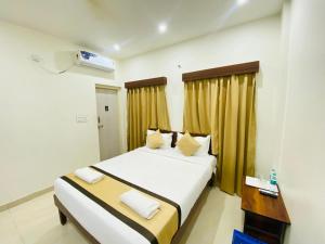 a hotel room with two beds and a desk and a bed at Hotel Safko Suites in Bangalore