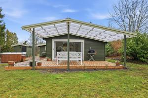 a pergola on a deck in a yard at Sommerhusidyl med vildmarksbad, strand og udebruser in Jægerspris