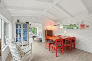 a dining room with a red table and chairs at Sommerhusidyl med vildmarksbad, strand og udebruser in Jægerspris