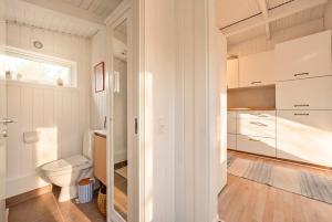 a white bathroom with a toilet and a window at Sommerhusidyl med vildmarksbad, strand og udebruser in Jægerspris +18 photos