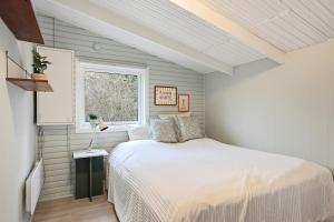 a bedroom with a white bed and a window at Sommerhusidyl med vildmarksbad, strand og udebruser in Jægerspris