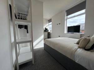 a white bedroom with a bed and a television at Camden St Accommodation in Derby