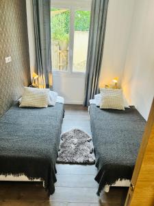two beds in a room with a window at Appartement jardin in Le Cannet