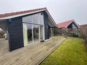 a house with a wooden deck in the yard at Marielyst feriehus in Bøtø By