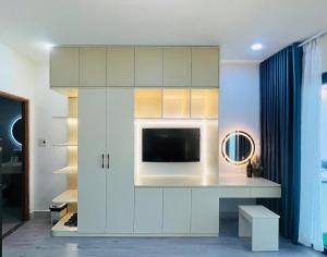 a living room with a tv in a white cabinet at Pony Bliss Haven - Sư Vạn Hạnh in Ho Chi Minh City