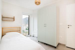a white bedroom with a bed and a window at Hisa Bubi in Tolmin