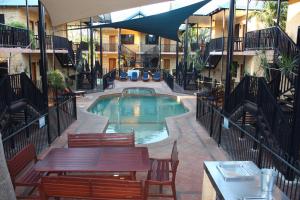 a pool with tables and chairs in a building at Apartments at Blue Seas Resort in Broome