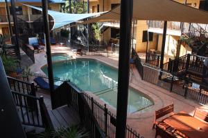 a patio area with a pool, chairs, and tables at Apartments at Blue Seas Resort in Broome