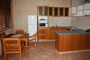 a kitchen with a table and a white refrigerator at Apartments at Blue Seas Resort in Broome