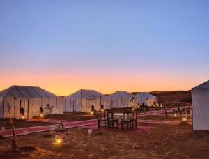 a row of tents in the desert at sunset at Lantern Luxury Camp in Merzouga