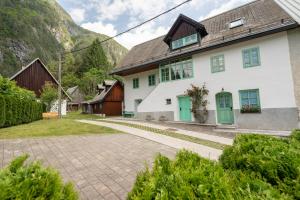 a white house with green doors and a mountain at Pri Dopivcu in Log pod Mangartom