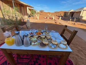 a table with utensils and plates of food on it at Lantern Luxury Camp in Merzouga