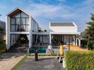 a house with a pool and a man standing next to it at 8 Valley KhaoYai in Ban Tha Chang