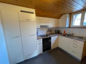 a kitchen with white cabinets and a wooden ceiling at Gemütliche 3,5 Zimmer Wohnung in Unterseen