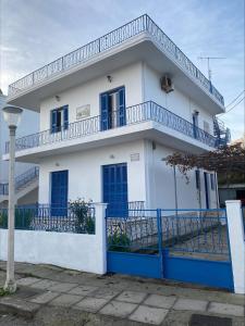 a white house with a blue fence in front of it at Traditional Town Garden Apartment in Rhodes Town