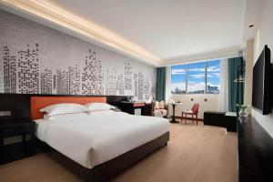 a bedroom with a large white bed and a desk at 花祺巨幕影院酒店 儋州那大镇夏日广场汽车站店 in Danzhou