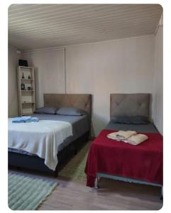 a bedroom with two beds and a red blanket at Condomínio Central Casa Luíza in Uruguaiana