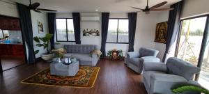 a living room with couches and chairs and windows at Bayon Country Villa in Phumĭ Trás Treăng
