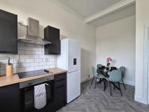 a kitchen with a table and a white refrigerator at Modern Top Floor 2BR apartment in Montrose