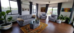 a living room with a couch and chairs and windows at Bayon Country Villa in Phumĭ Trás Treăng