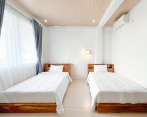 two beds in a room with white walls and a window at La Casa de Maria in Komodo Labuan Bajo Airport