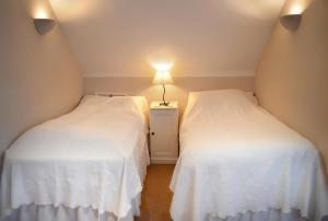 two beds in a room with a lamp on a night stand at Lammas Park House in Dawlish