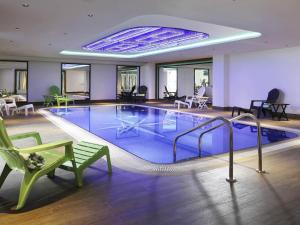 a pool in a hotel with a green chair and a bench at Ibis Styles Dubai Jumeira in Dubai