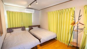 two beds in a room with yellow curtains at mintstay kochi in Kochi