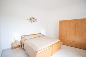 a bedroom with a bed and a wooden cabinet at SA DOMU DE S'ORTU in Bari Sardo +9 photos
