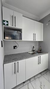a white kitchen with a sink and a microwave at HUZULA Royal Residence in Empangeni