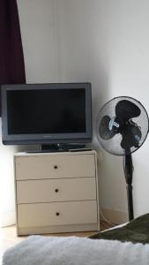 a television on top of a dresser with a fan at Modern Studio Near Gatwick in London Gatwick Airport