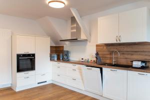 a white kitchen with white cabinets and a sink at Wolke 7 – PEAK Andreasberg in Sankt Andreasberg