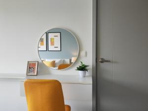 a mirror on a white desk with a yellow chair at Cozy Breeze Onnut 21 in Amphoe Phra Khanong