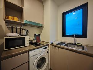 a kitchen with a washing machine and a microwave at Cozy Breeze Onnut 21 in Amphoe Phra Khanong