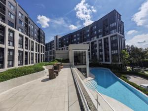 a view of a building with a swimming pool at Cozy Breeze Onnut 21 in Amphoe Phra Khanong