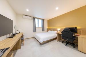 a bedroom with a bed and a desk with a computer at Agabara Gangneung in Gangneung