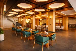 a restaurant with wooden tables and green chairs at Pride Premier Darjeeling in Darjeeling