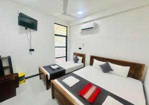 a bedroom with two beds and a flat screen tv at Dilithy Paradise in Trincomalee