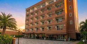 a large building with a palm tree in front of it at Valhalla Pattaya Hotel in Jomtien Beach