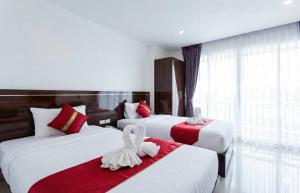 a hotel room with two beds with red and white sheets at Valhalla Pattaya Hotel in Jomtien Beach