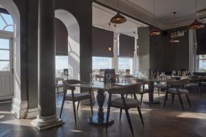 a dining room with tables and chairs and windows at The Burlington in Worthing