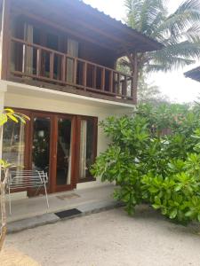 a house with a balcony on the side of it at Biru Meno Beach Bungalows in Gili Meno