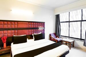 a bedroom with a large bed and a large window at Super Collection O Maninagar Formerly Park Land in Ahmedabad