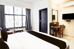 a hotel room with a bed and a desk and a television at Super Collection O Maninagar Formerly Park Land in Ahmedabad +36 photos