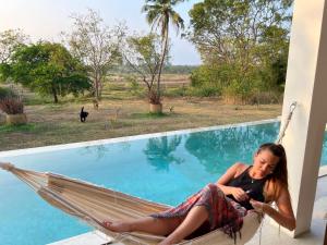 a woman sitting in a hammock next to a pool at Giri Villa in Tangalle