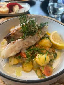 a plate of food with a piece of fish and a lemon at Dabanović House in Virpazar +36 photos