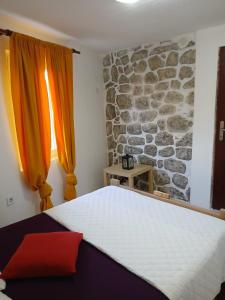 a bedroom with a bed and a stone wall at Dabanović House in Virpazar